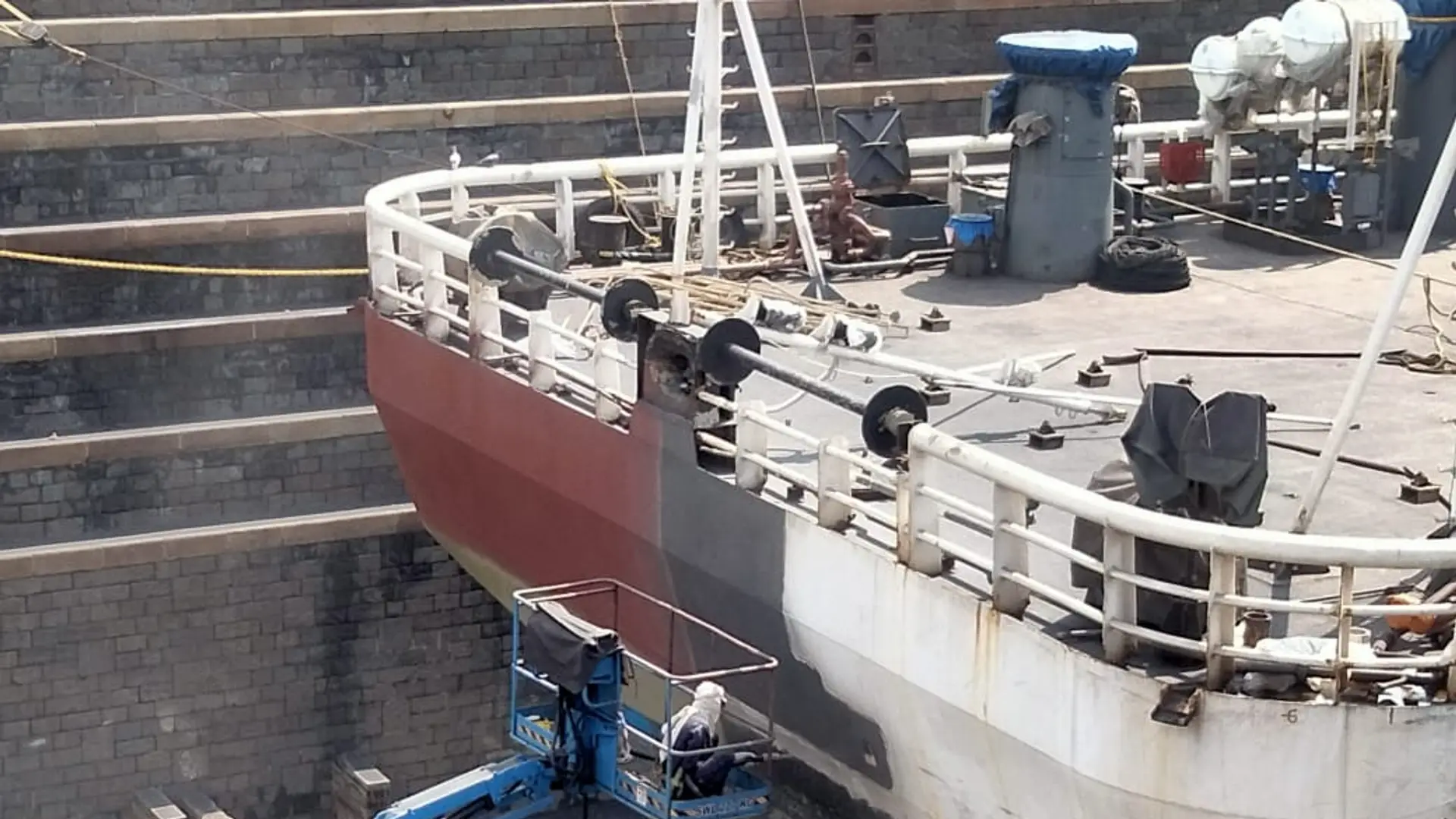 Marine technician grit blasting a vessel hull